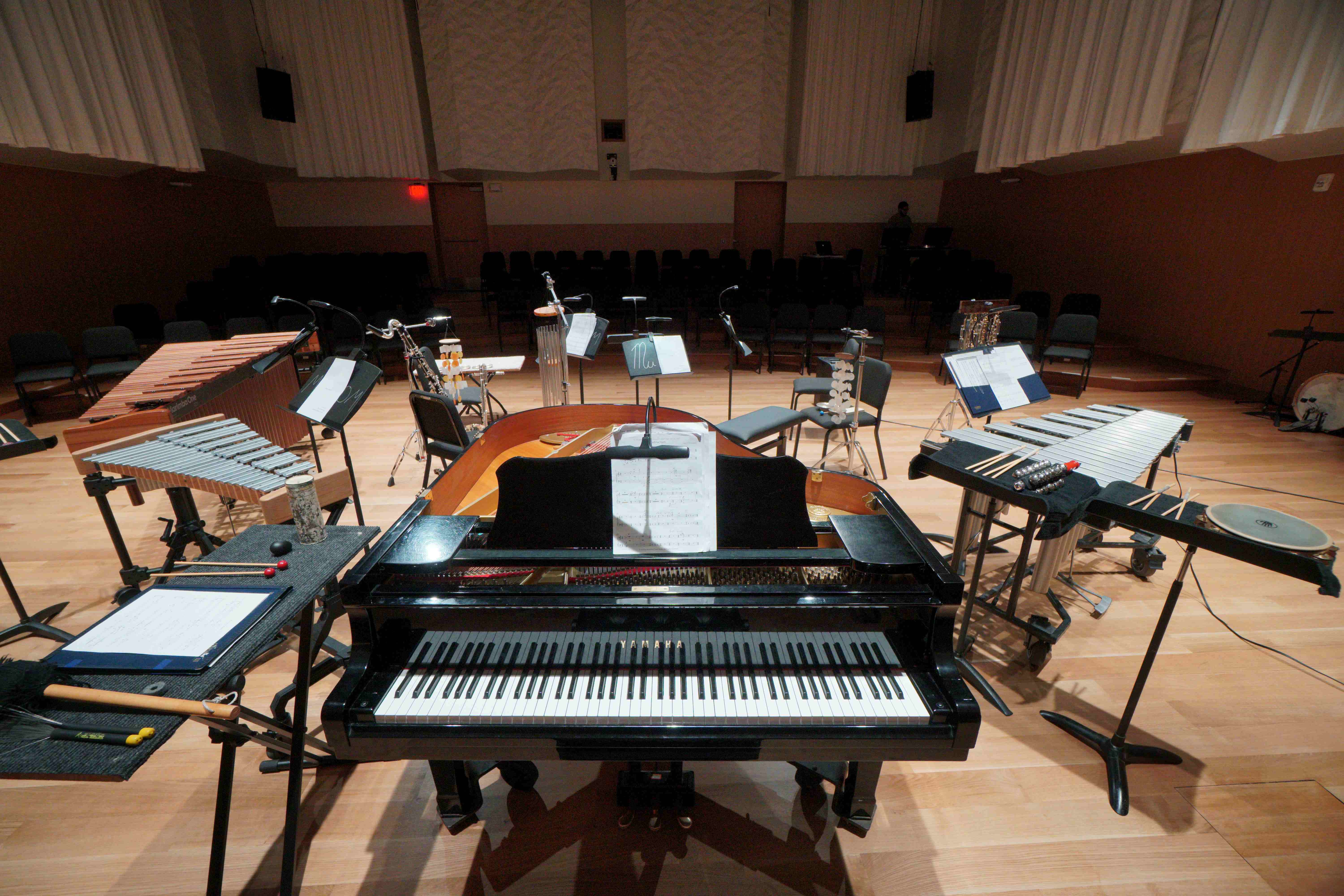 Instruments set up for an esnemble performance with a piano in the foreground