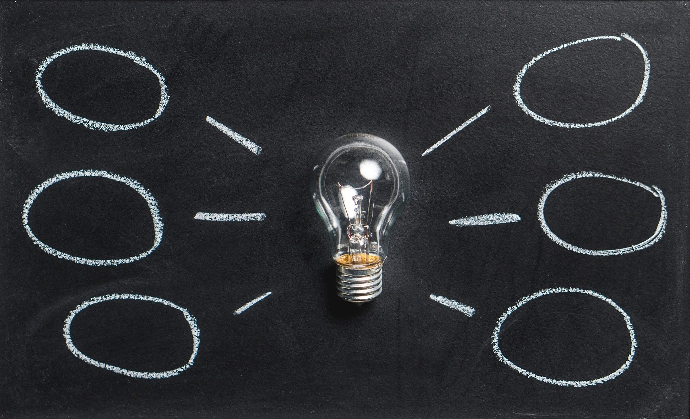 A light bulb drawn on a blackboard, surrounded by several circles, symbolizing ideas or brainstorming concepts.
