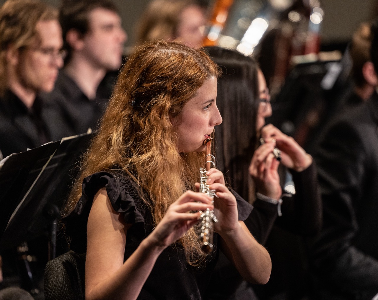 A photo of a lady playing her instrument in an orchestra
